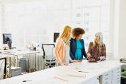 Drei Frauen stehen bei einer Büro-Besprechung Drei Frauen stehen bei einer Büro-Besprechung